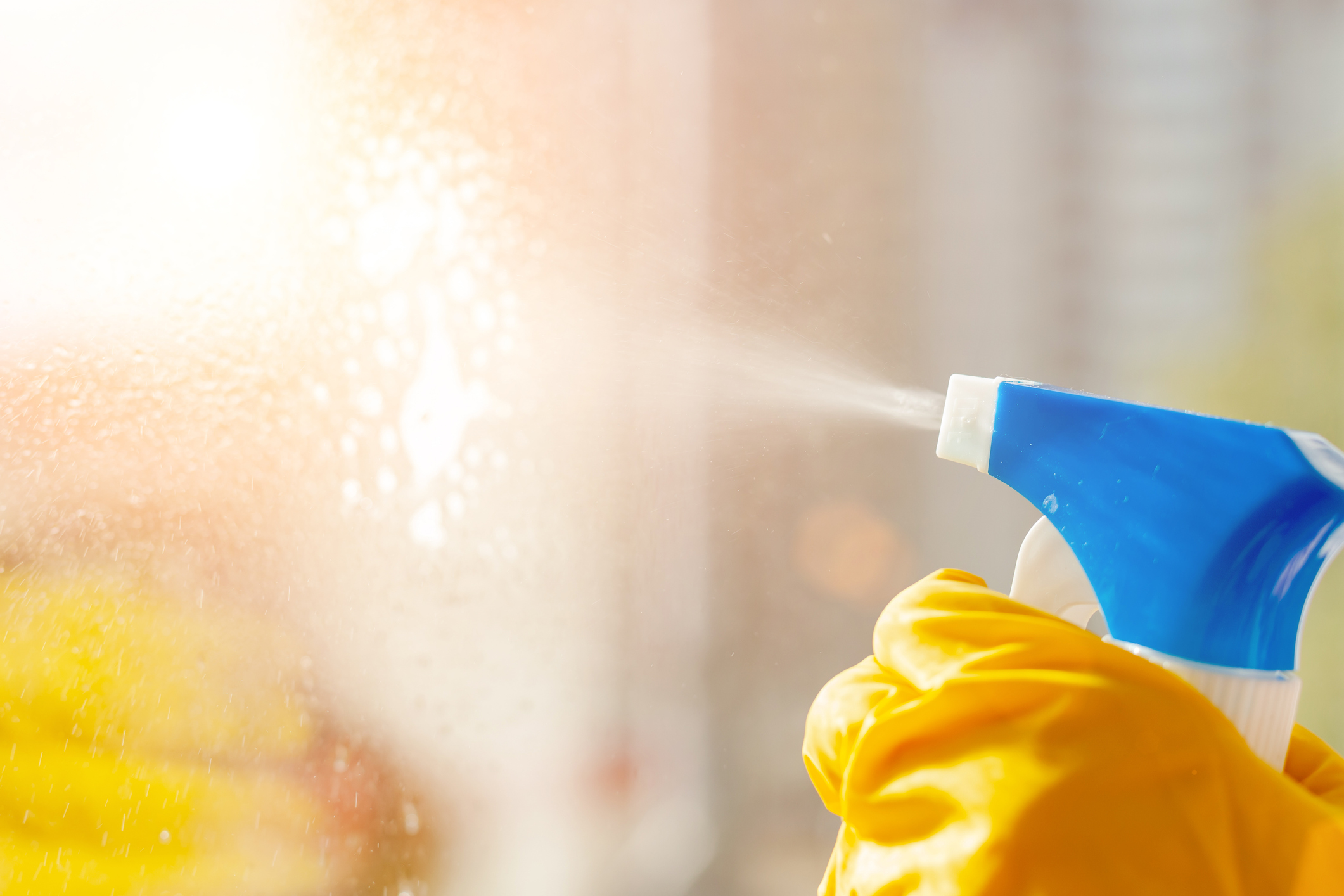 hand in a yellow rubber glove wipes the window close-up